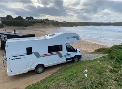 a white camper truck parked on a beach at Raffy The Motorhome in St Merryn