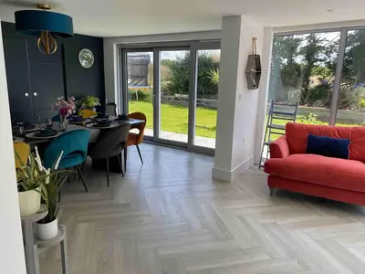 a living room with a red couch and a table at Detached 4 Bed House with large gardens and Hot Tub in St Merryn