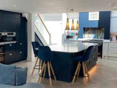 a kitchen with a blue island with blue chairs at Detached 4 Bed House with large gardens and Hot Tub in St Merryn