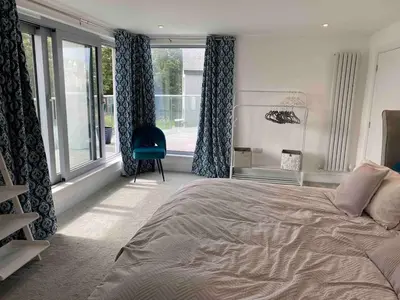 a bedroom with a large bed and a large window at Detached 4 Bed House with large gardens and Hot Tub in St Merryn