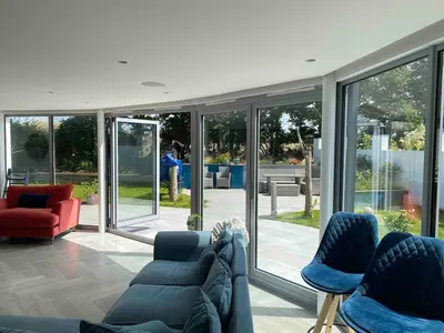 a living room with a couch and chairs and sliding glass doors at Detached 4 Bed House with large gardens and Hot Tub in St Merryn