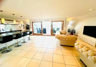 a large living room with a couch and a kitchen at Seaforth - Stunning Beach View Free Parking in Perranporth