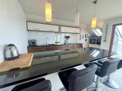 a large kitchen with a large counter with chairs at Seaforth - Stunning Beach View Free Parking in Perranporth
