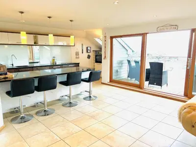 a kitchen with black chairs and a large window at Seaforth - Stunning Beach View Free Parking in Perranporth