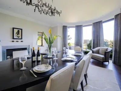 a dining room with a table and chairs and a fireplace at Woodlands in Mawnan