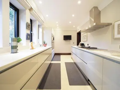 a kitchen with white counters and a long counter top at Woodlands in Mawnan