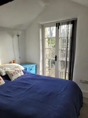 a bedroom with a blue bed and a window at Carbis Bay Cabins in Carbis Bay
