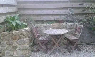 a table and two chairs next to a stone wall at Carbis Bay Cabins in Carbis Bay