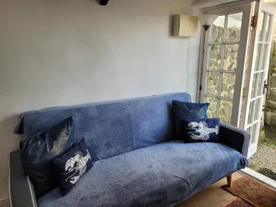 a blue couch with pillows on it in a room at Carbis Bay Cabins in Carbis Bay