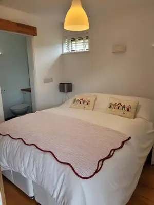 a bedroom with a white bed with a pink blanket at Carbis Bay Cabins in Carbis Bay