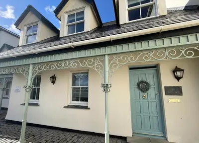 a white house with a green door on a street at Beachfront Retreat in Falmouth