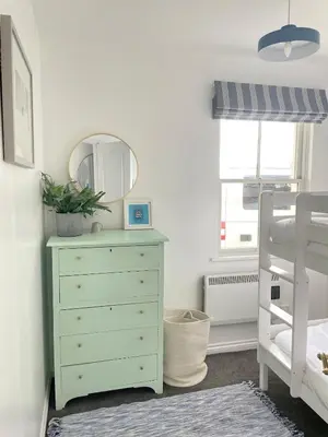 a bedroom with a green dresser and a mirror at Beachfront Retreat in Falmouth