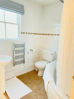 a white bathroom with a toilet and a sink at Beachfront Retreat in Falmouth