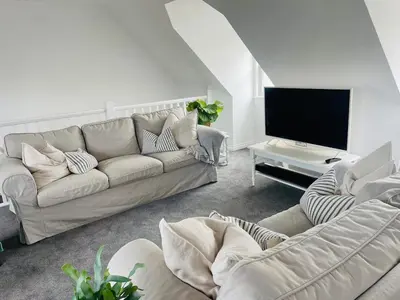 a living room with a couch and a flat screen tv at Beachfront Retreat in Falmouth