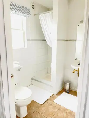 a white bathroom with a toilet and a sink at Beachfront Retreat in Falmouth