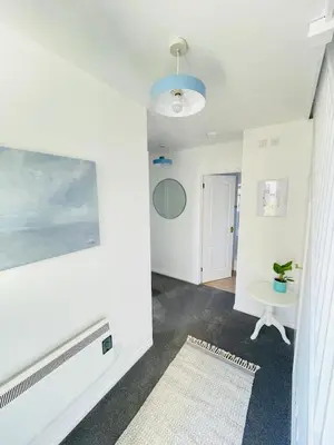 a living room with a tv and a white wall at Beachfront Retreat in Falmouth