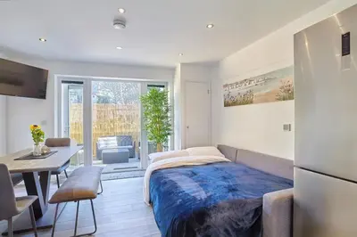 a bedroom with a bed and a table and a kitchen at 2022 Two Bed Stylish House Near Beach in Hayle