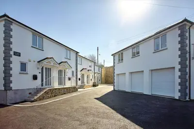 a row of white buildings with garages at 2022 Two Bed Stylish House Near Beach in Hayle