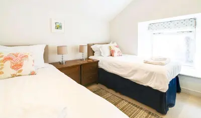 a bedroom with two beds and a window at Harbour Front Flat in Porthleven - Next to shops in Porthleven