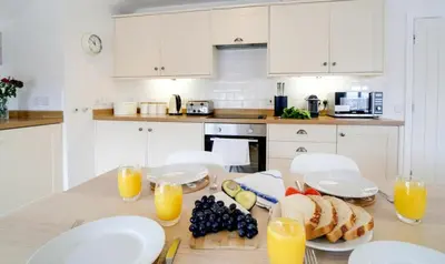 a kitchen with a table with bread and orange juice at Harbour Front Flat in Porthleven - Next to shops in Porthleven