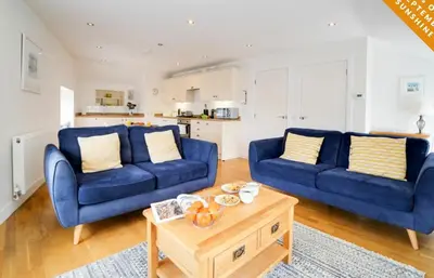 a living room with two blue couches and a coffee table at Harbour Front Flat in Porthleven - Next to shops in Porthleven