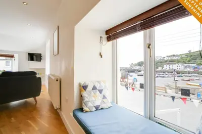 a living room with a large window and a couch at Harbour Front Flat in Porthleven - Next to shops in Porthleven