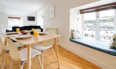 a dining room and living room with a table and chairs at Harbour Front Flat in Porthleven - Next to shops in Porthleven
