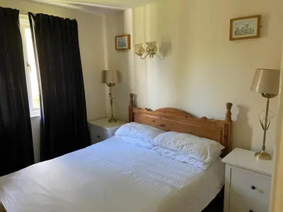 a bedroom with a bed with white sheets and a window at Bolthole in Hayle