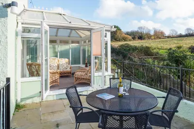 a patio with a table and chairs and a conservatory at The Moorings just across from Fowey in Fowey