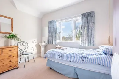a white bedroom with a bed and a window at The Moorings just across from Fowey in Fowey