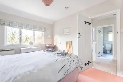 a white bedroom with a large bed and a bathroom at The Moorings just across from Fowey in Fowey