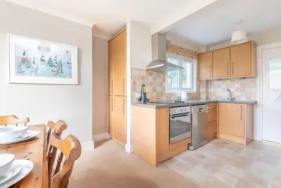 a kitchen with wooden cabinets and a table and a dining room at The Moorings just across from Fowey in Fowey