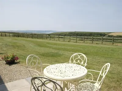 a white table and chairs with a field of grass at Skylark Hayle far views over St Ives Bay in Camborne