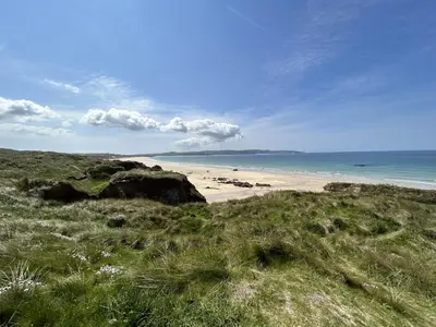 a beach with rocks and the ocean on a sunny day at Skylark Hayle far views over St Ives Bay in Camborne