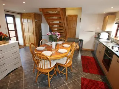 a kitchen with a wooden table and chairs and a kitchen with stairs at Skylark Hayle far views over St Ives Bay in Camborne