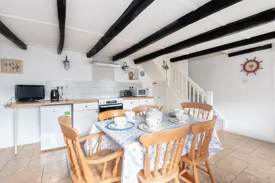a kitchen with a table with chairs and a kitchen with a stove at Warren Cottage in the pretty village of Polperro in Polperro