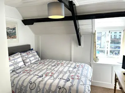 a bedroom with a bed with a comforter and a window at Warren Cottage in the pretty village of Polperro in Polperro