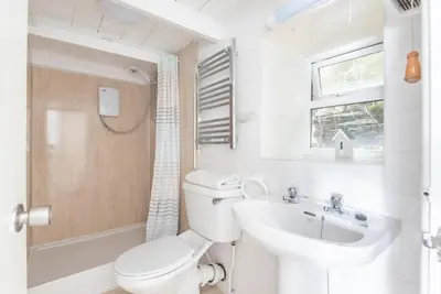 a white bathroom with a toilet and a sink at Warren Cottage in the pretty village of Polperro in Polperro