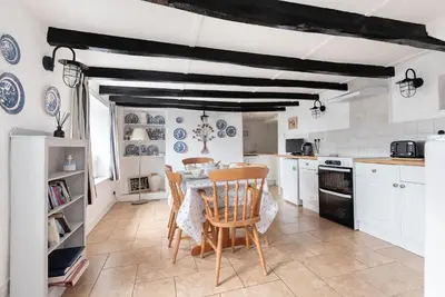 a kitchen with white cabinets and a table and chairs at Warren Cottage in the pretty village of Polperro in Polperro
