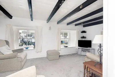 a living room with a tv and two windows at Warren Cottage in the pretty village of Polperro in Polperro