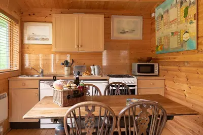 a kitchen with a table and chairs in a cabin at The Cabin at Little Bosveal near the Helford River....lovely location in Mawnan Smith