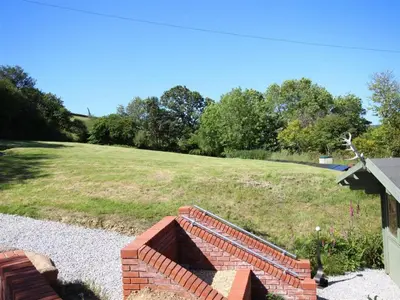 a brick wall next to a field of grass at The Cabin at Little Bosveal near the Helford River....lovely location in Mawnan Smith
