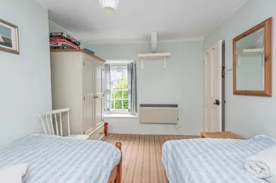 a bedroom with two beds and a window at White Pebble Cottage popular village - Port Isaac in Port Isaac