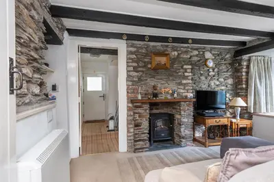 a living room with a stone wall with a fireplace at White Pebble Cottage popular village - Port Isaac in Port Isaac