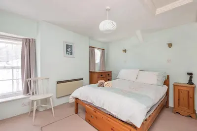 a bedroom with a large bed and a chair at White Pebble Cottage popular village - Port Isaac in Port Isaac