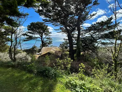 a house on a hill with trees and the ocean at Windwhistle coastal views of Looe Bay cliffs in Saint Martin