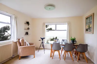 a living room with a table and chairs at Windwhistle coastal views of Looe Bay cliffs in Saint Martin