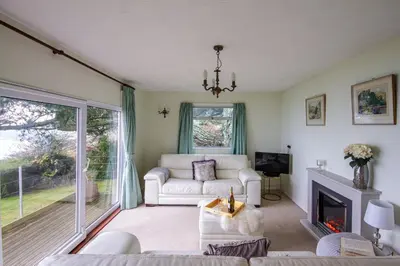 a living room with a couch and a fireplace at Windwhistle coastal views of Looe Bay cliffs in Saint Martin