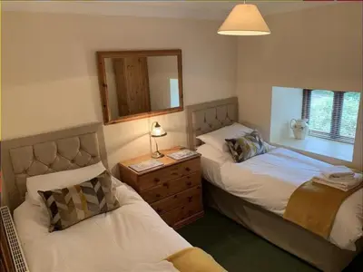 a bedroom with two beds and a mirror at Treveglos Barn on the coast road close to Harlyn Bay and Padstow. in St Merryn