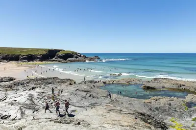 a group of people walking on the rocks at a beach at Treveglos Barn on the coast road close to Harlyn Bay and Padstow. in St Merryn